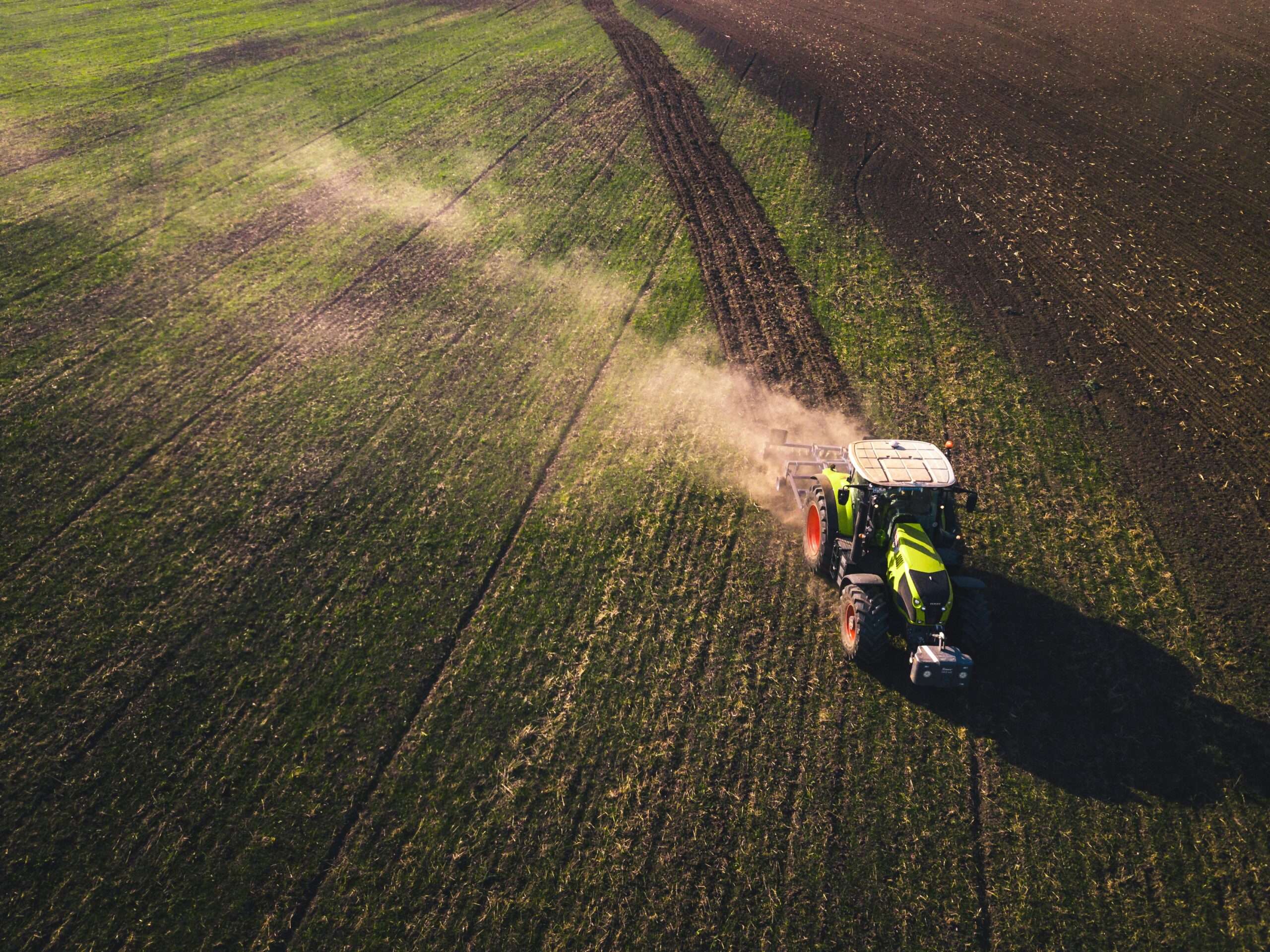 Aerial view of a tractor crossing a green arable field during farm pest control in Wiltshire
