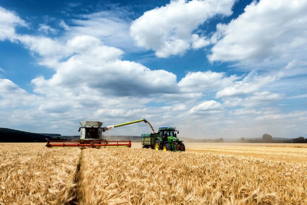 Combine harvester and tractor in a grain field, representing farm pest control surveys, visits and retainers in Swindon & Wiltshire.